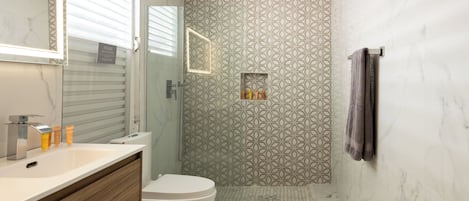 Un baño con ducha, inodoro y tocador.
