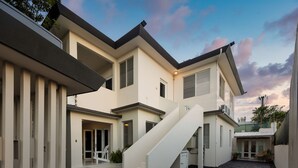 Ein modernes, zweistöckiges Haus mit einer Treppe, die zum oberen Stockwerk führt, einer überdachten Terrasse und einem gepflasterten Innenhof.