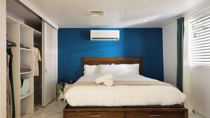 Ein Schlafzimmer mit einem hölzernen Bett, weißer Bettwäsche, einem Einbauschrank und einer blauen Akzentwand.