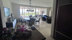 Un comedor amplio con una gran mesa y sillas, una cocina con encimeras de granito, y vistas al exterior a través de amplios ventanales.