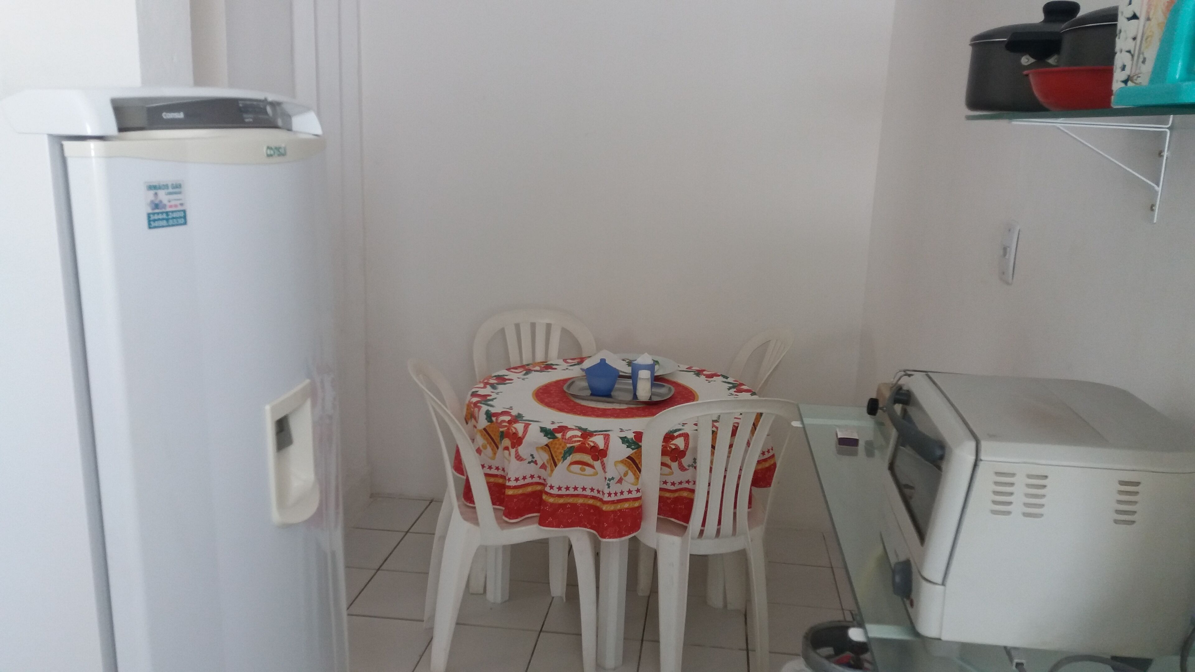 Et lille køkken med et køleskab, en mikrobølgeovn og et bord med stole.