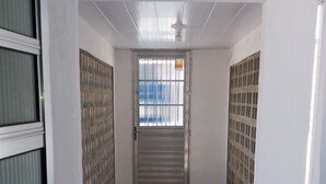 A room with a tiled floor, a green bench, and a barred window.