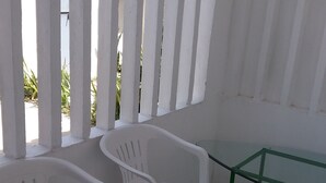 A room with white plastic chairs, a glass table, and a green metal frame.