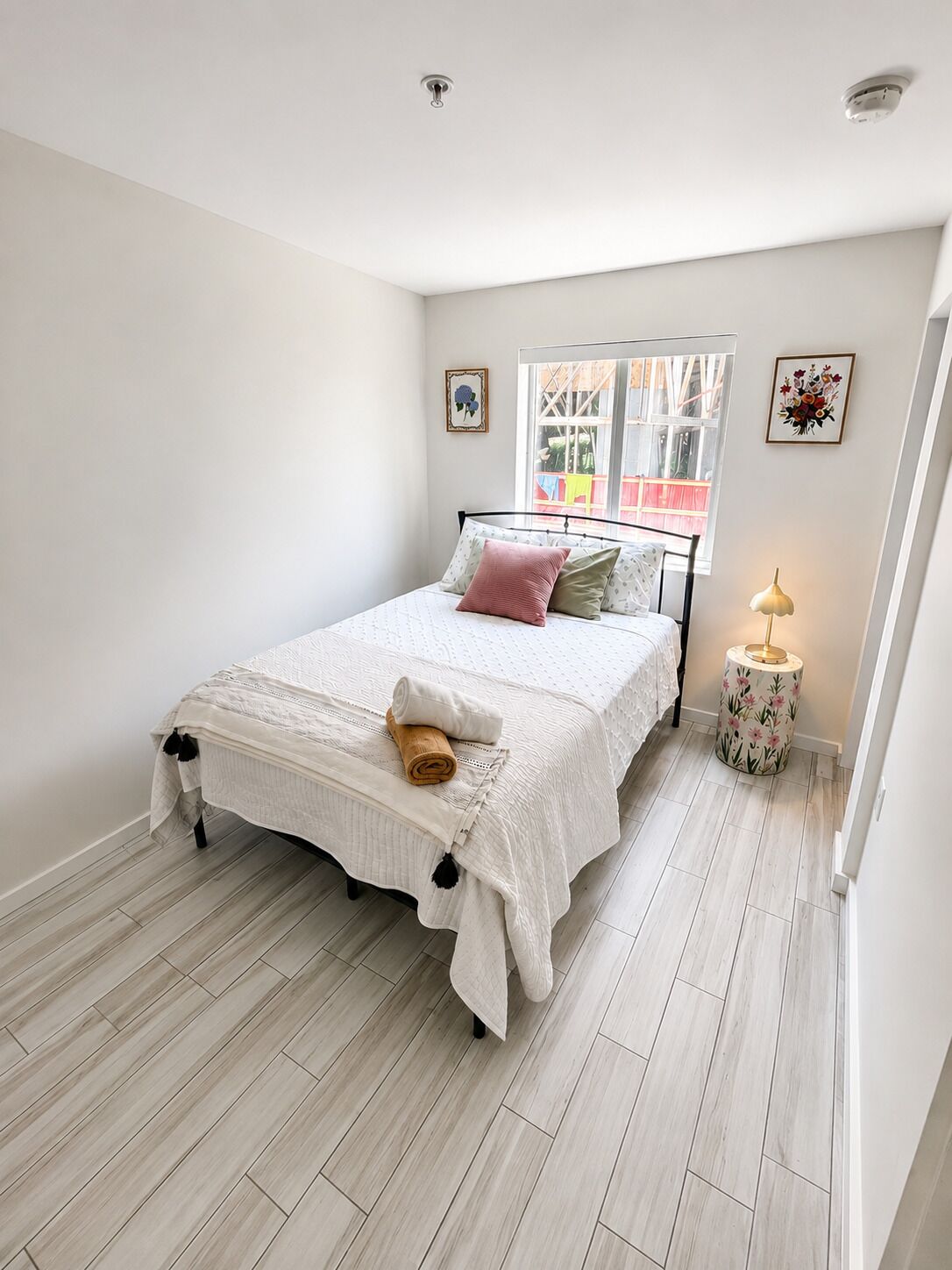 A bedroom with a bed, a bedside lamp, and a window.