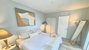 A bedroom with a bed, bedside tables, a lamp, a painting, and a mirror. - Penthouse, Waterviews, Private Rooftop, Free Parking,Vibrant Miami neighborhood (Miami)