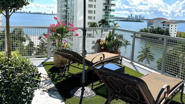 A balcony with outdoor furniture, a large umbrella, and a view of the city skyline across the water. - Penthouse, Waterviews, Private Rooftop, Free Parking,Vibrant Miami neighborhood (Miami)