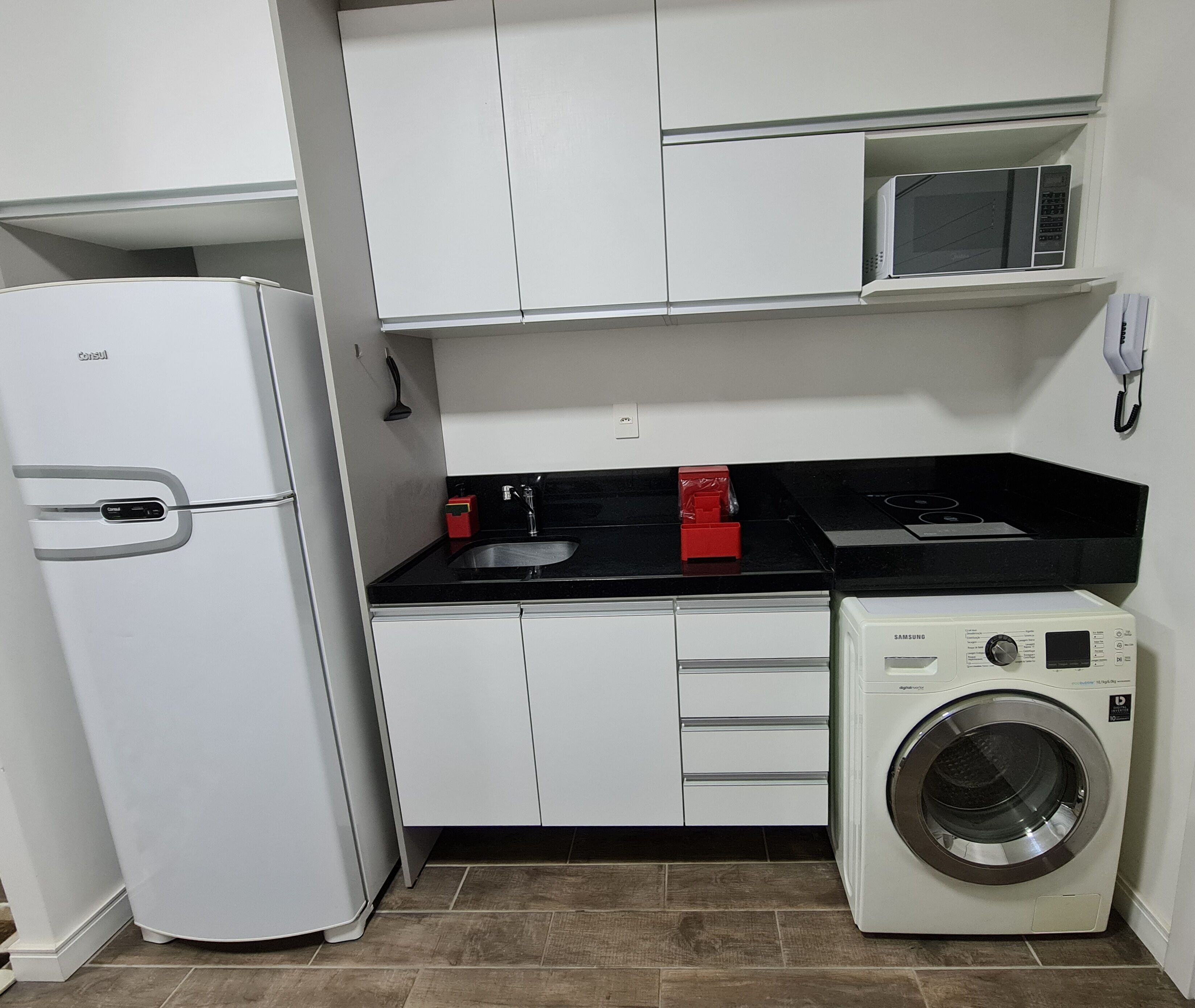 A compact kitchen with a refrigerator, microwave, stove, and washing machine.