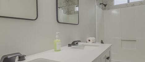 A modern bathroom with two sinks, a mirror, a toilet, and a shower area.