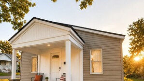 Une maison de plain-pied avec un porche à l’avant, des fondations en briques et un petit jardin.