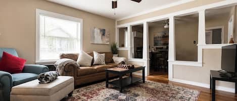A living room with a ceiling fan, a sofa, a coffee table, and a patterned rug.