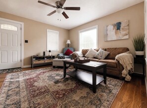 A living room with a sofa, coffee table, and a patterned rug.