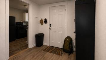 A hallway with a black refrigerator, a trash bin, and a backpack on the floor.