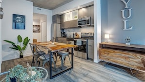 A modern kitchen with stainless steel appliances, a dining area with a wooden table and chairs, and a wall with the letters 'YUL' displayed. - Montreal - C Lofts Le Smith 2 Bedroom (Montréal)