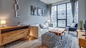 A modern living room with a sofa, coffee table, and a wooden side table. - Montreal - C Lofts Le Smith 2 Bedroom (Montréal)