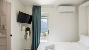 Ein Hotelzimmer mit Bett, Fernseher, Klimaanlage, einem Fenster mit Vorhängen und Meerblick.