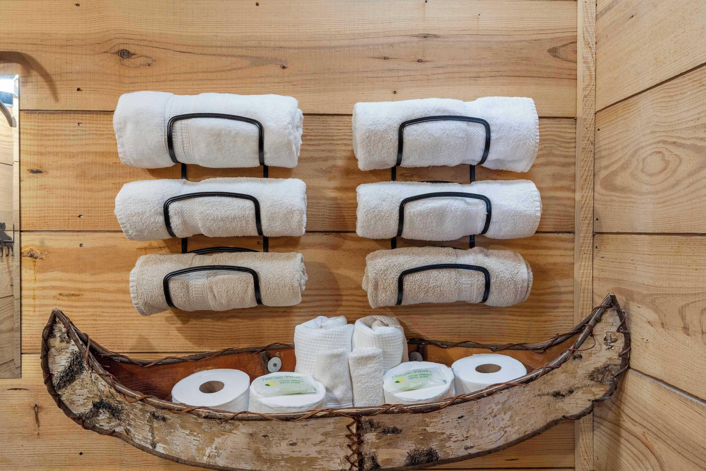 A wooden cabin interior with towels and toiletries arranged on shelves and a wooden boat-shaped container.