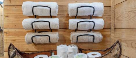 A wooden cabin interior with towels and toiletries arranged on shelves and a wooden boat-shaped container.
