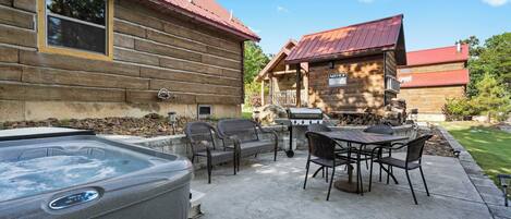 A wooden cabin with a hot tub and outdoor seating area.