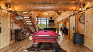 Een houten interieur met een pooltafel, houten wanden en een kroonluchter.