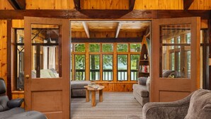 A cozy cabin interior with a wooden interior, a large window, and a fireplace. - Hot Tub, Water Amenities, Lakeshore Cottage (Newaygo)