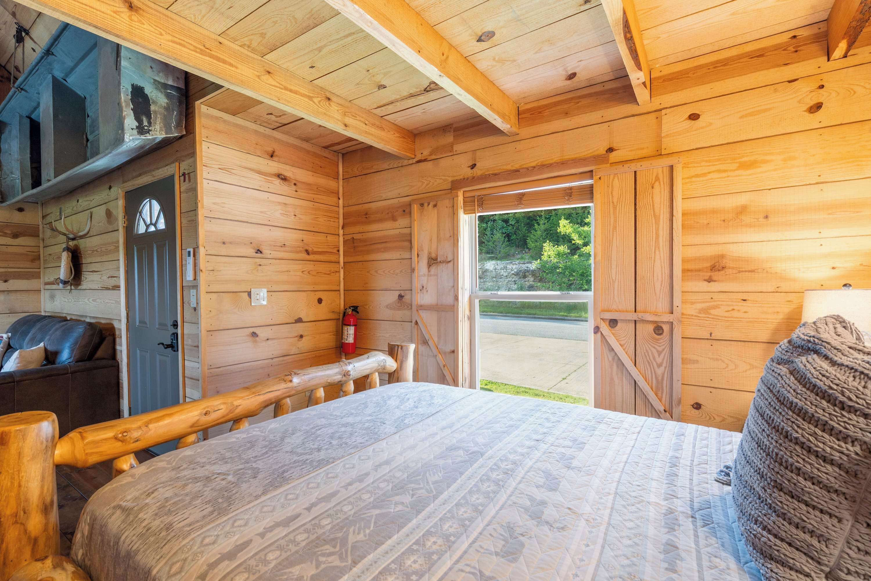 A wooden cabin room with a bed, a door, and a window.