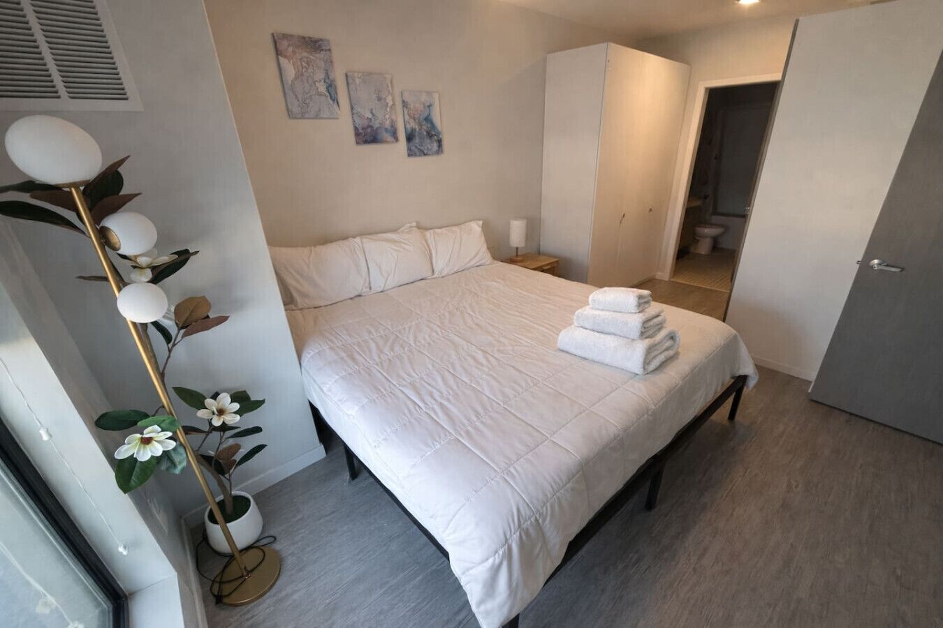 Un dormitorio con cama, mesitas de noche, armario y una planta.