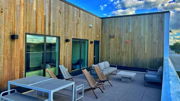 An outdoor patio with a wooden wall, glass sliding doors, and seating areas including a table and chairs. - Your home away from home (Des Moines)