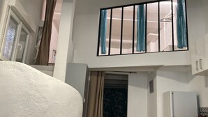 A room with a bed, a washing machine, and a window with curtains.