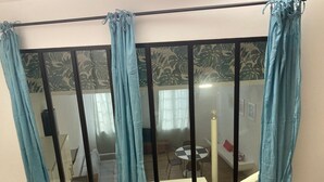 A room with a sliding glass door featuring blue curtains, a patterned wallpaper, and a view of a dining area with a table and chairs.