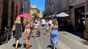 A street with pedestrians, buildings, and outdoor seating areas.