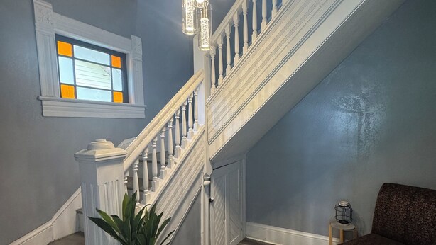 A staircase with white railings and a potted plant at the bottom.