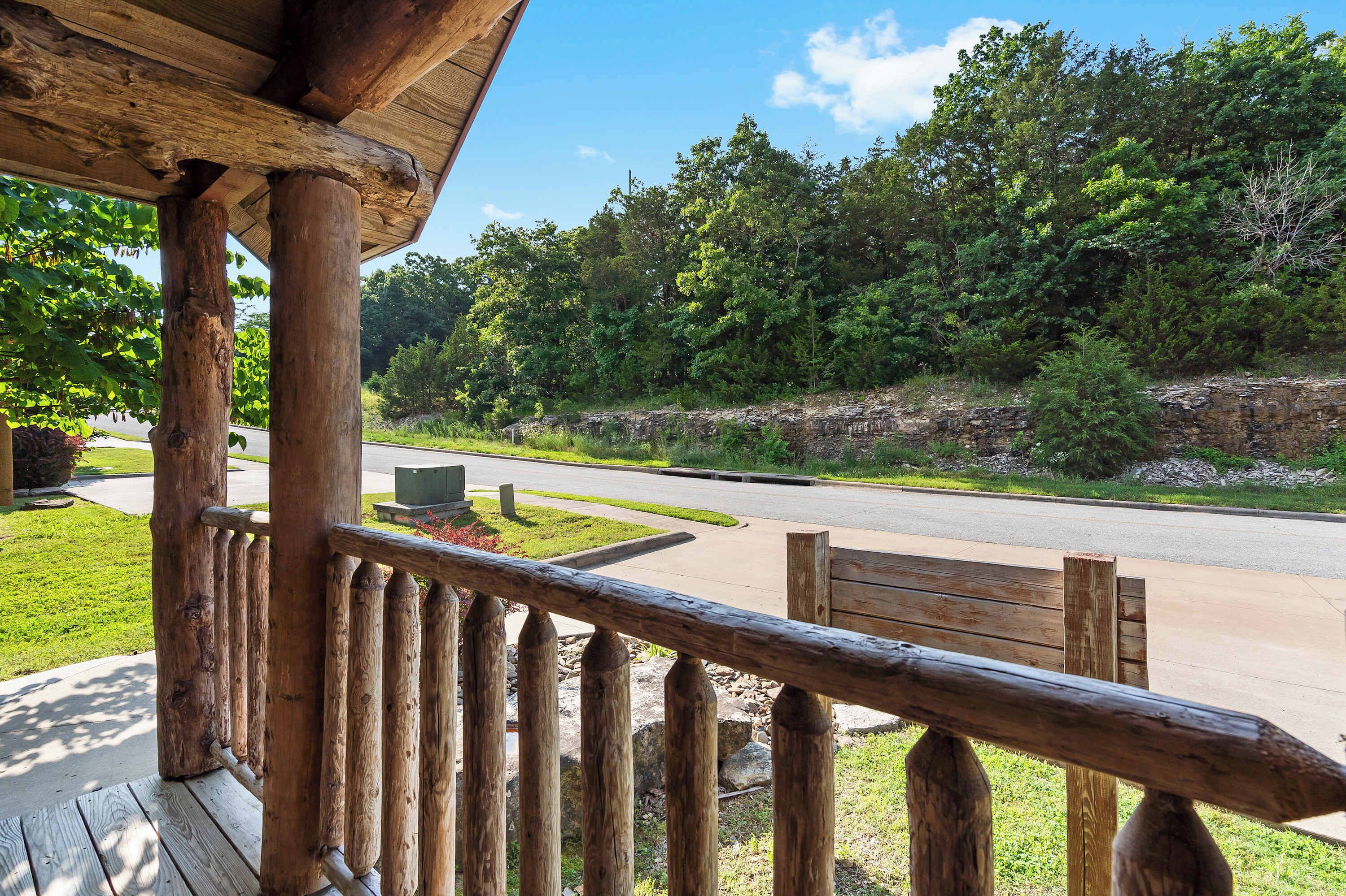 A wooden porch with a view of a road and forest.