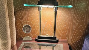 Un bureau avec un plateau en verre et une lampe.
