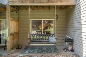 A porch with a wooden swing, a patterned rug, and a grill. - Bigfoots' Bluff Retreat (Branson)