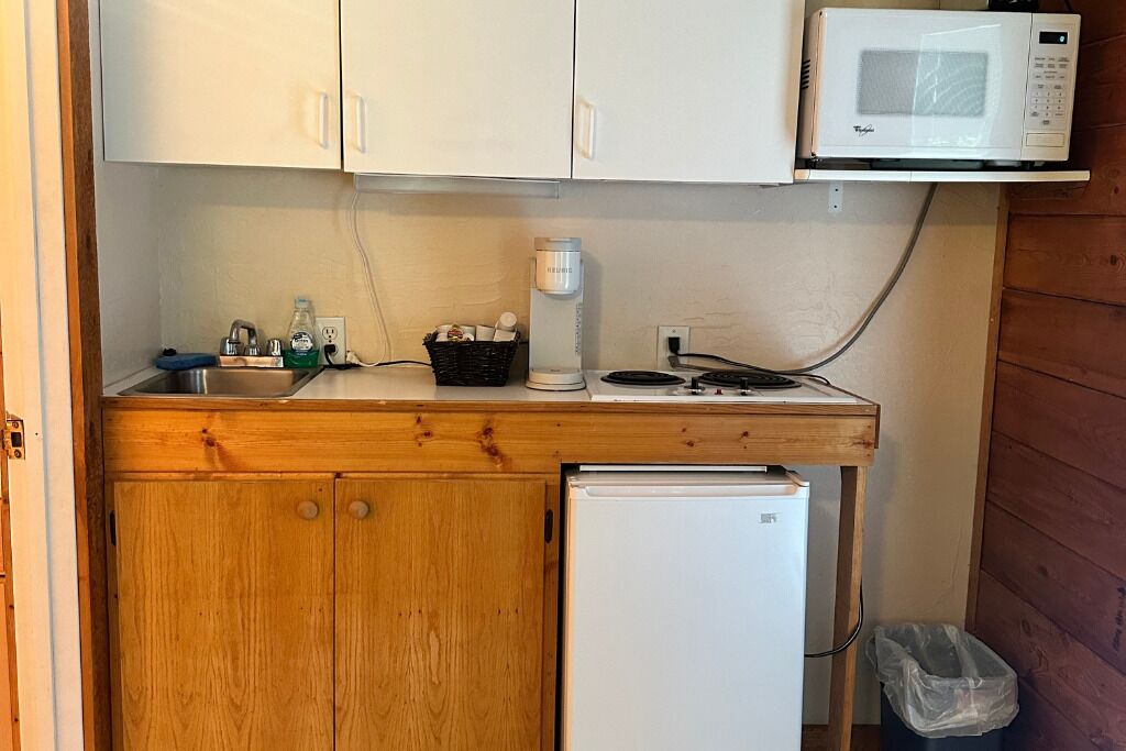 A compact kitchenette with a microwave, a small refrigerator, a sink, and a wooden countertop.