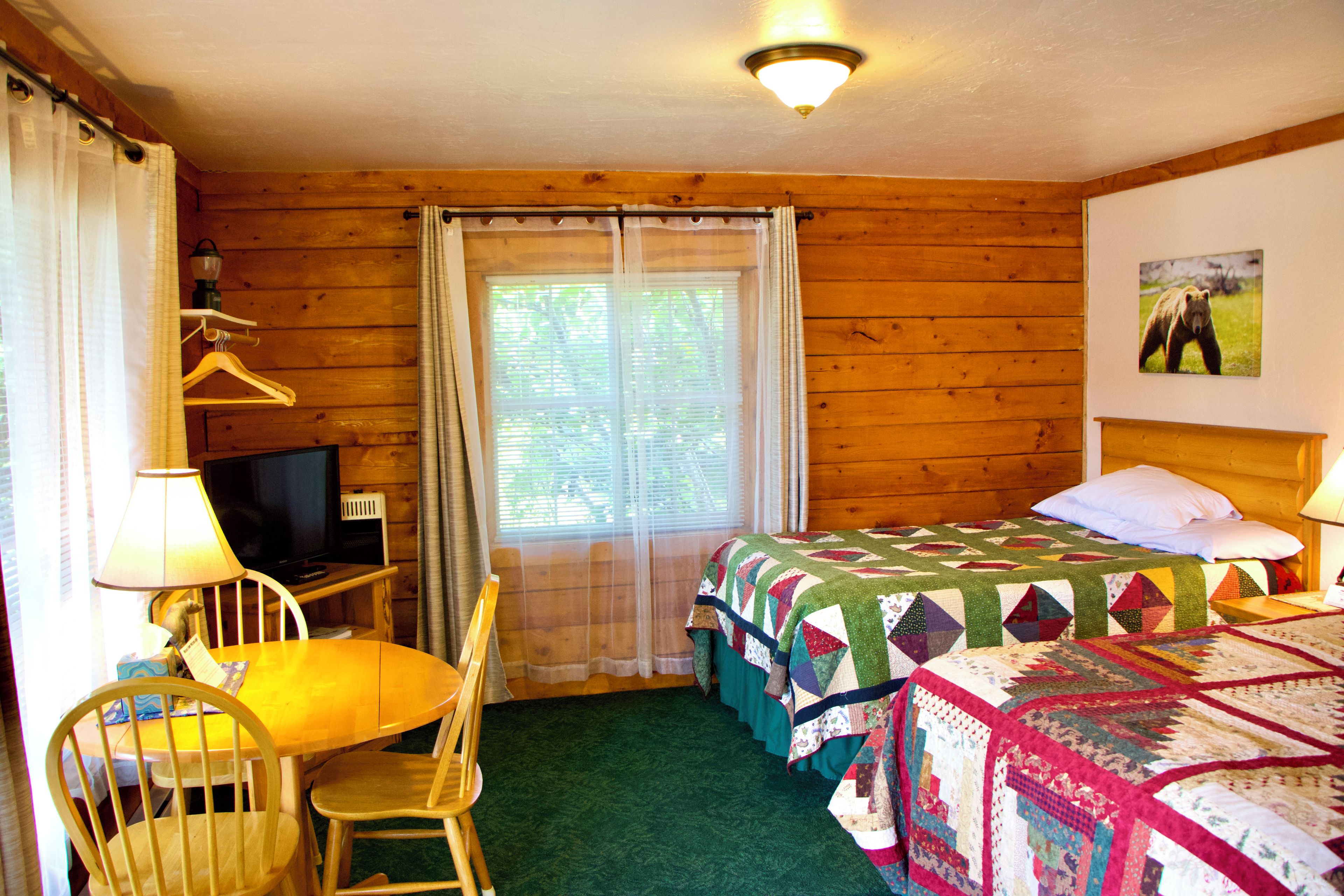 A room with a bed, a desk with a television, a chair, and a window with curtains.