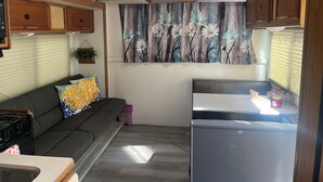 Une cuisine compacte pour camping-car, équipée d’un réfrigérateur, d’une cuisinière et de placards en bois.