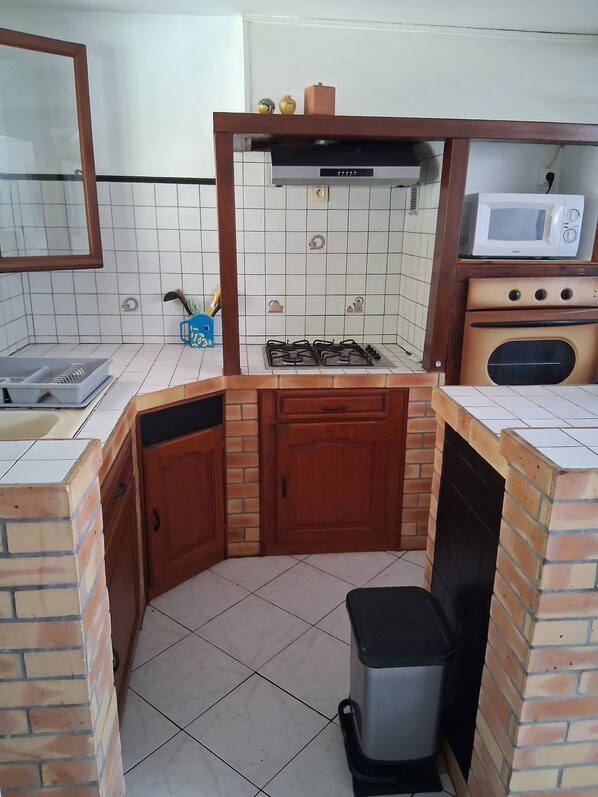 Eine kompakte Küche mit Gasherd, Mikrowelle und Backofen.