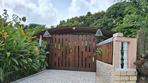 A gated entrance with a tiled pathway leading to a building. - Charming gîte, in a lush countryside setting yet close to all amenities. (Le Lamentin)