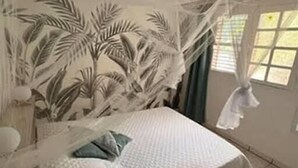 A bedroom with a bed, a window, and a curtain. - Charming gîte, in a lush countryside setting yet close to all amenities. (Le Lamentin)