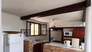 A compact kitchen with a refrigerator, microwave, and tiled backsplash. - Charming gîte, in a lush countryside setting yet close to all amenities. (Le Lamentin)