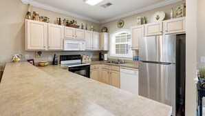 A kitchen with light wooden cabinets, stainless steel appliances, and decorative items on the countertops. - Lucky Eagle @ Myrtlewood Golf (Myrtle Beach)