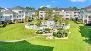 A multi-story residential building with a swimming pool, well-maintained lawns, and a fenced play area. - Lucky Eagle @ Myrtlewood Golf (Myrtle Beach)