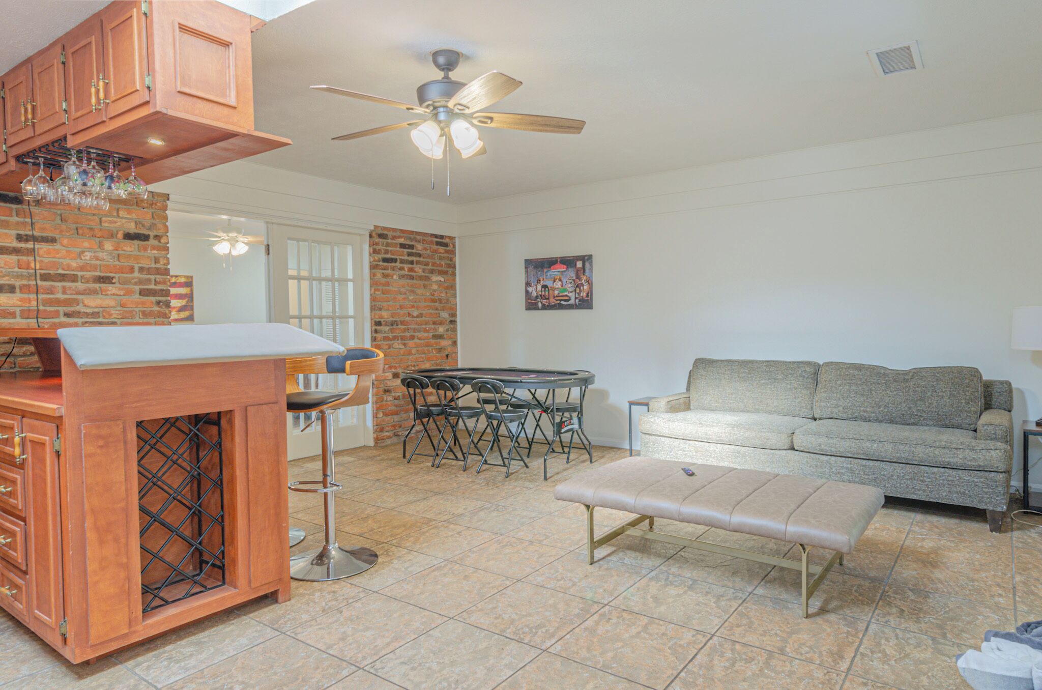 Una cocina con pared de ladrillo, barra de madera y zona de comedor con mesa y sillas.