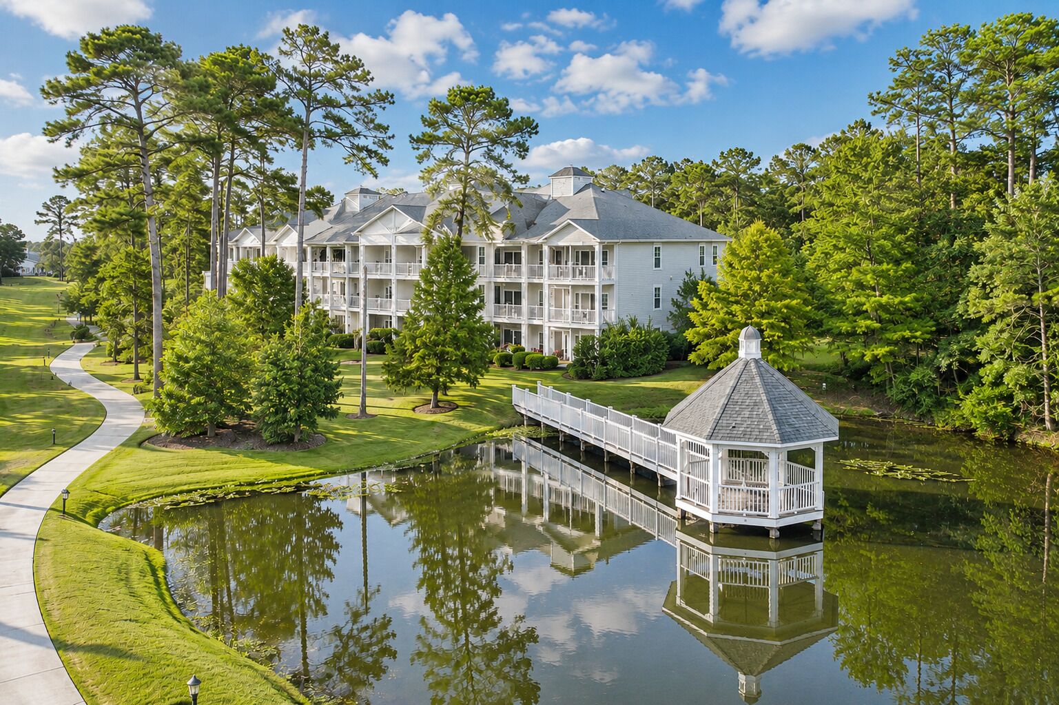 A residential complex with multiple buildings, a pond, and a gazebo.