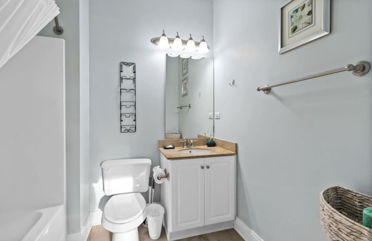 A bathroom with a toilet, sink, and mirror.