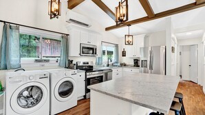 Una cocina moderna con gabinetes blancos, electrodomésticos de acero inoxidable y una isla central.