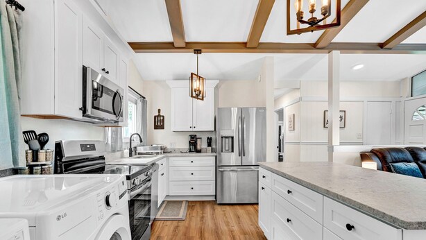 Una cocina moderna con armarios blancos, electrodomésticos de acero inoxidable y suelo de madera.