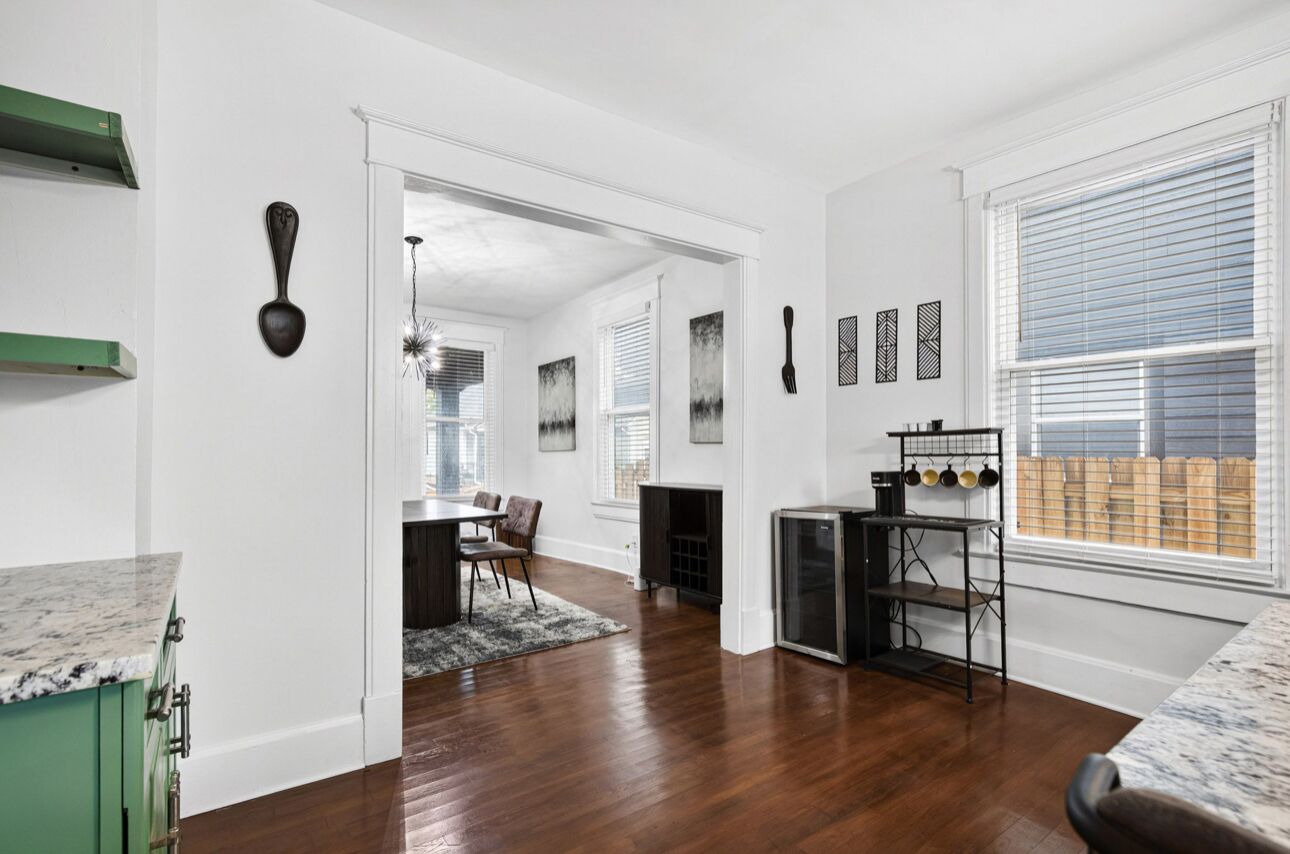 A spacious kitchen with wooden flooring, a dining area with a chandelier, and a view of a wooden deck through large windows.