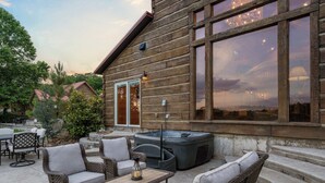 A log cabin with a patio area featuring wicker furniture and a hot tub. - Buffalo Lodge - Stay for 8 (Branson)